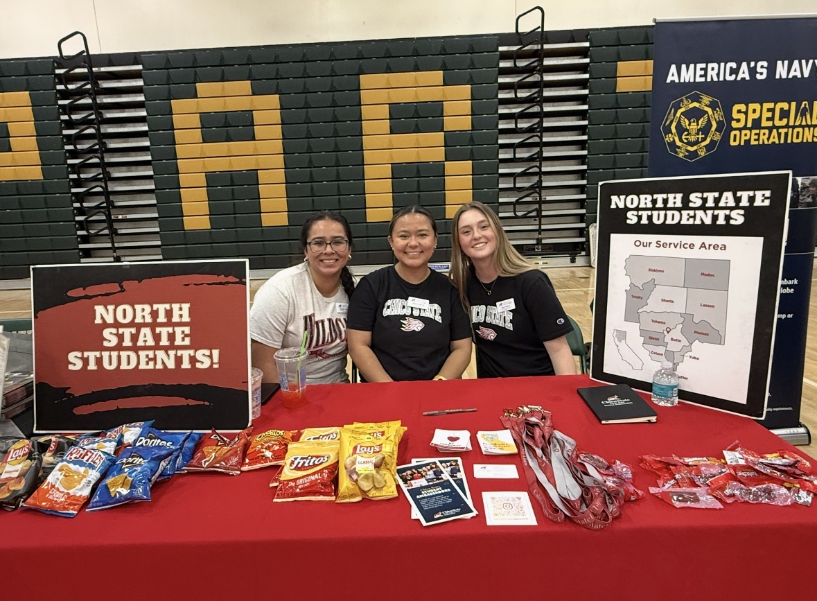 three college students sit at a table with a sign that says North State Students