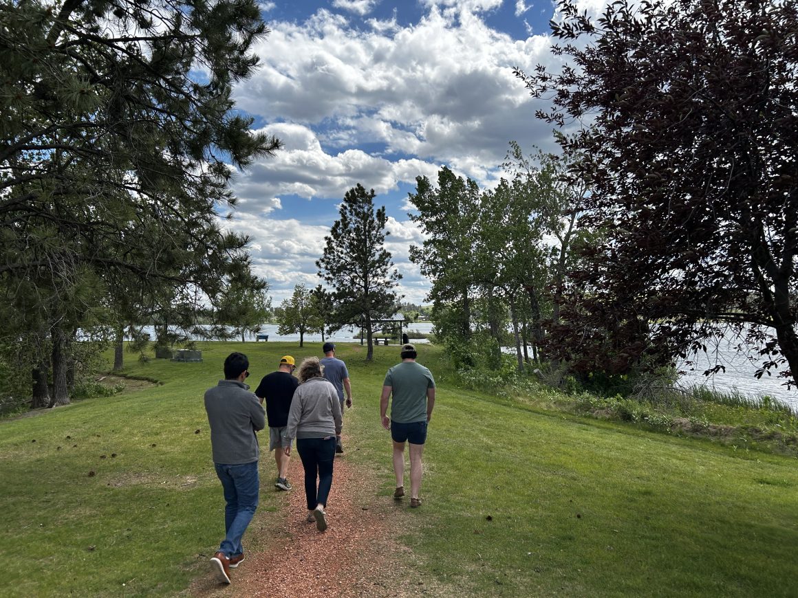 a group of people walk down a path toward the water in a park
