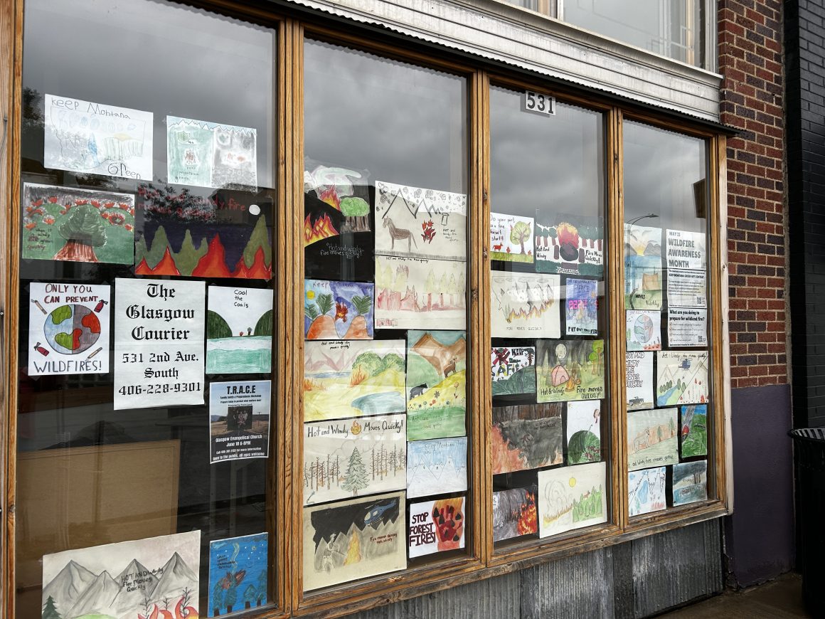 children's colorful drawings cover a shop window with a sign labeling it as the Glasgow Courier